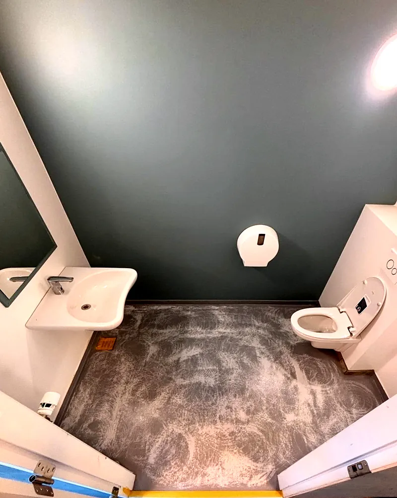 Før: Toiletrum på skole med slidt gulv under renovering