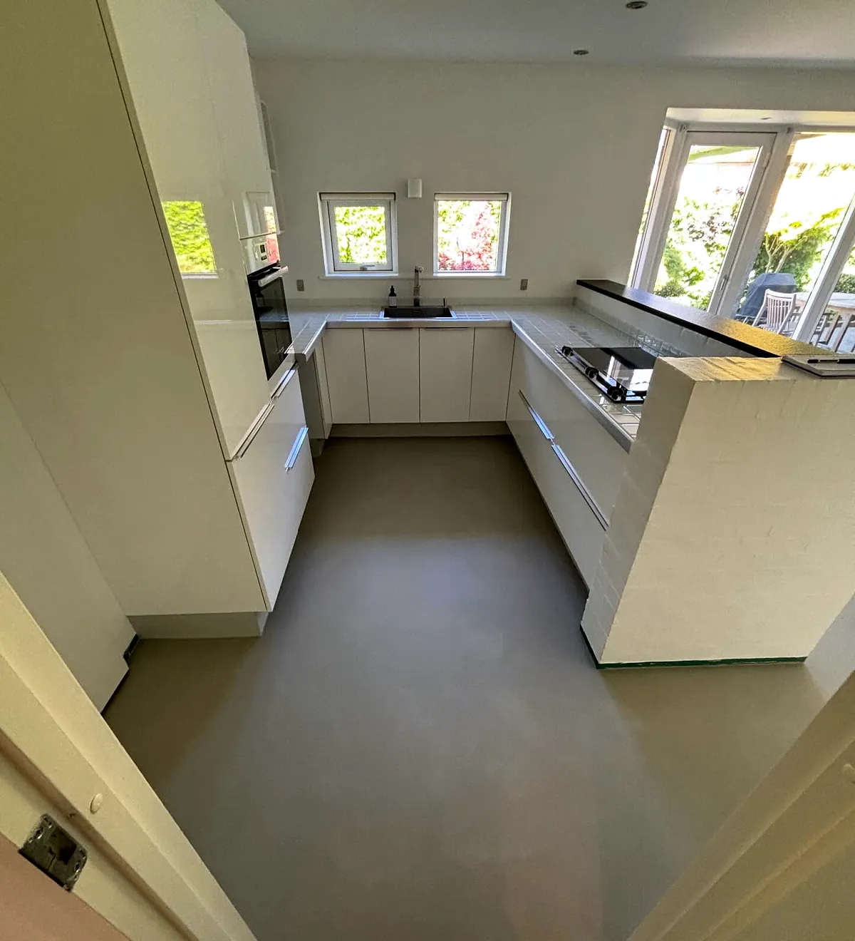 Køkken og alrum med nyt designgulv i gråt PU og udsigt til haven